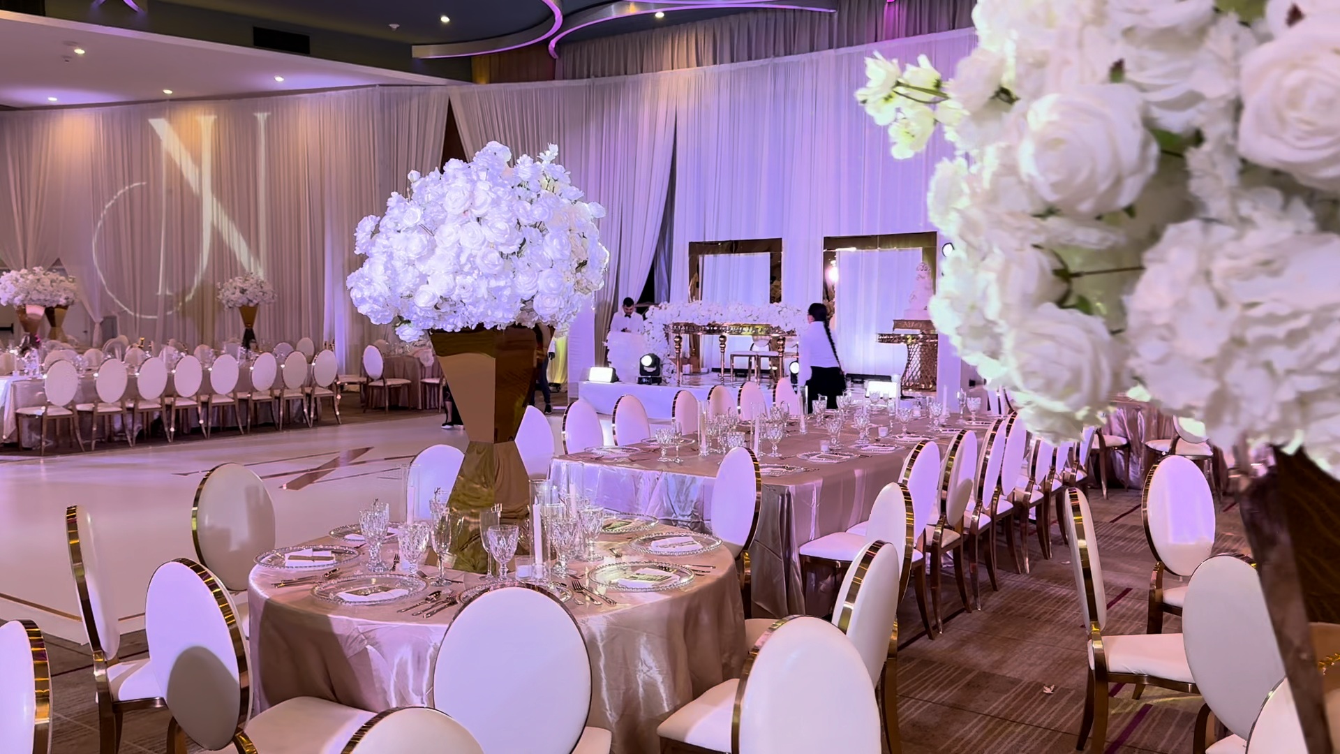 Wedding dance floor beside the sweetheart stage, with moving heads and a large monogram on the draping